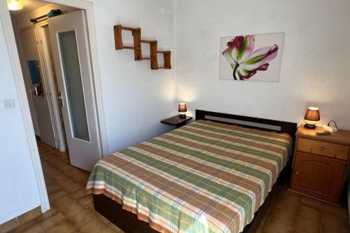 - une chambre avec un lit doté d'un couvre-lit rayé dans l'établissement Naturiste Cap d'Agde Villa Héliovillage 10, au Cap d'Agde