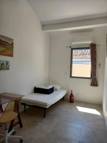 une petite pièce avec un lit et une fenêtre dans l'établissement maison de village avec patio, à Aspiran