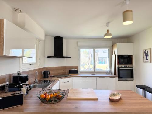 - une cuisine avec un bol de fruits sur une table en bois dans l'établissement Charmante maison près de la plage, Sainte Marine, à Combrit