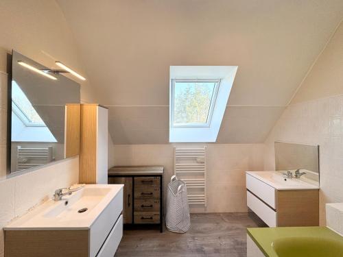 une salle de bain avec deux lavabos et une fenêtre dans l'établissement Charmante maison près de la plage, Sainte Marine, à Combrit
