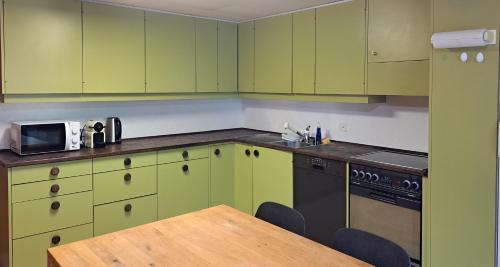 格林德尔瓦尔德Chalet Engi Apt. 3 for up to 8 People的厨房配有绿色橱柜和木桌