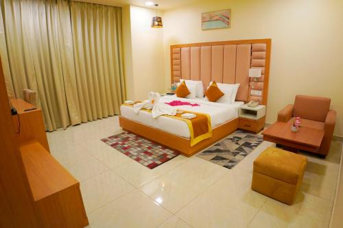a bedroom with a large bed and a chair at Hotel Cheer Royale in Bareilly