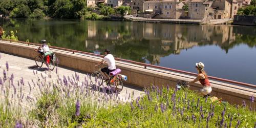 three people riding bikes on a bridge over a river at Le Dolmen, charme sport et détente in Saint-Chels