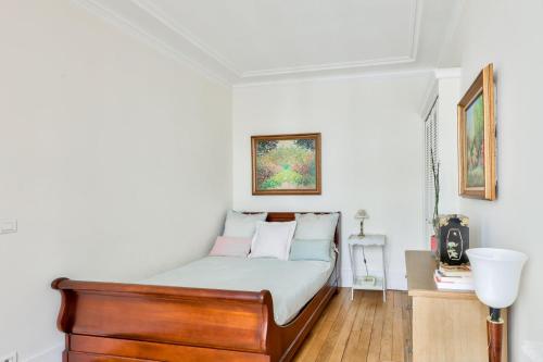 une chambre avec un lit avec une tête de lit en bois dans l'établissement Stunning Parisian 1BR Flat near Sacré-Cœur, à Paris