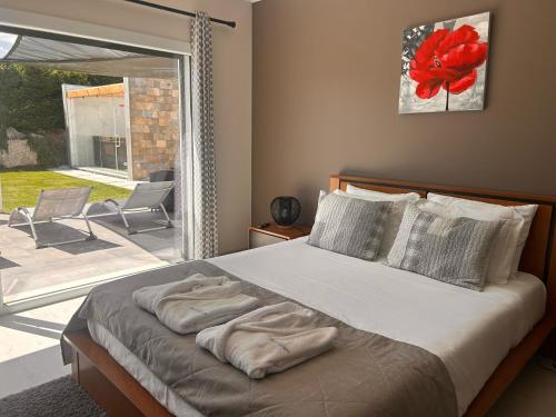 a bedroom with a bed and a large window at Villa Mila Piscina e Jacuzzi in Salir de Matos