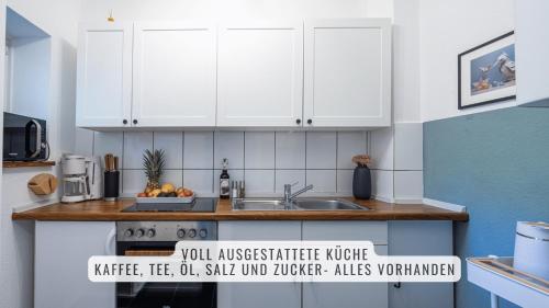 a kitchen with white cabinets and a sink at have-a-nice-Stay - nahe Bahnhof Ahrensburg - 20 Minuten nach Hamburg - trotzdem ruhig gelegen - 6 Minuten zu Fuß ins Zentrum Ahrensburg - modern eingerichtet in Ahrensburg