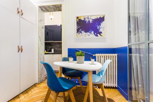 une salle à manger avec une table blanche et des chaises bleues dans l'établissement Moderne apartment - 1BR 4P - AC - Champs-Élysées, à Paris