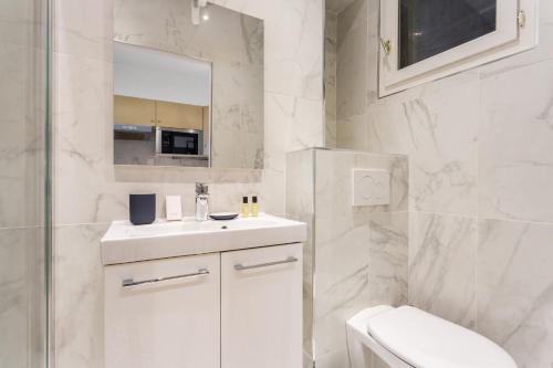 une salle de bain blanche avec un lavabo et un miroir dans l'établissement Cosy Studio - 4P - Palais des Congres, à Paris