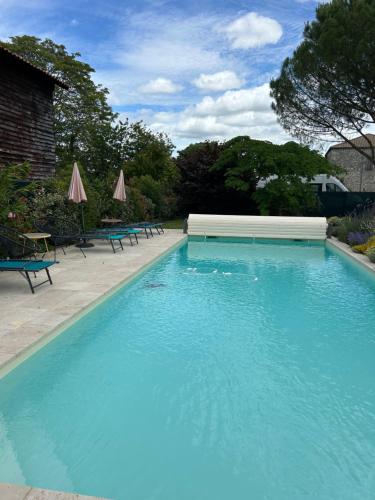 a large blue swimming pool with chairs and umbrellas at La Grange de la Maison des chats - Gîte en Quercy in Saint-Amans-du-Pech