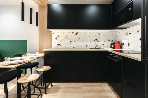 une cuisine avec des placards noirs et une table avec des tabourets dans l'établissement Beautiful Appt -1BR-4P- Porte d'Auteuil-Boulogne, à Boulogne-Billancourt