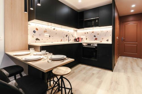 une cuisine avec des armoires noires et une table avec des chaises dans l'établissement Beautiful Appt -1BR-4P- Porte d'Auteuil-Boulogne, à Boulogne-Billancourt