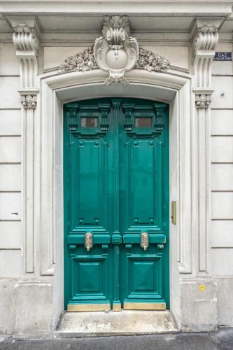 une porte verte sur un bâtiment blanc avec une lumière au-dessus dans l'établissement Cosy and peaceful studio - 2P - Paris Center, à Paris