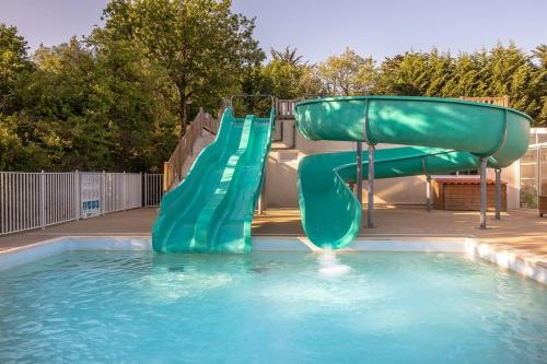 a green water slide in a swimming pool at Camping les Alouettes - Bretignolles-sur-Mer in Bretignolles-sur-Mer