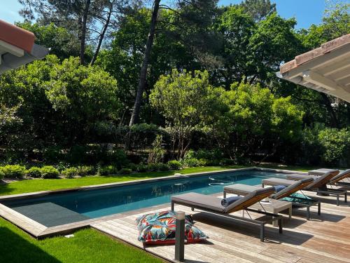 - une piscine avec des chaises longues à côté d'une cour dans l'établissement Villa Romaline - Plage Pereire - Piscine chauffée, à Arcachon
