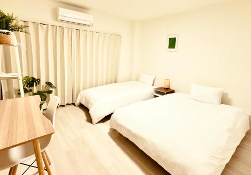 a white room with two beds and a table at F Hotel 新築アパート 近くに品川と羽田空港 无料駐車場予約必須 in Tokyo