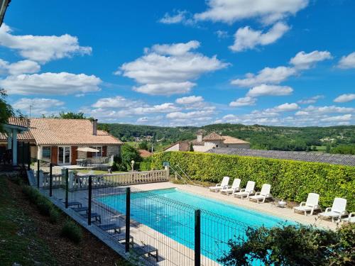 une piscine avec des chaises et une maison dans l'établissement Les gites du Treil - 2 Grandes piscines privées- 9 chambres - 20 personnes, à Courbiac