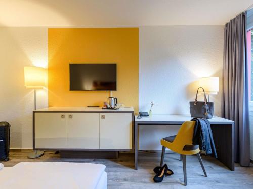 a bedroom with a desk and a yellow chair at Mercure Hotel Köln West in Cologne