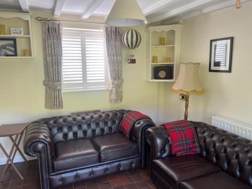 a living room with a leather couch and a lamp at Riverside Cottage in Ironbridge