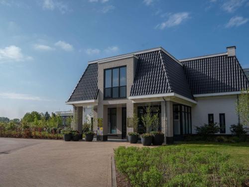 a white house with a black roof at Hotel Ter Zand - Handwritten Collection in Burgh Haamstede