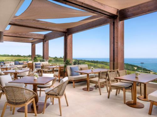 a restaurant with tables and chairs and the ocean at Fairmont La Hacienda Costa del Sol in Alcaidesa