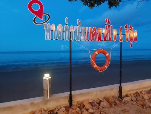 a sign for a beach with a life preserver and a candle at หาดกำนันแคมป์ปิ้ง&ซีฟู๊ด in Ban Laem Sui