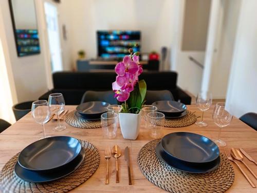 a table with plates and glasses and a vase of flowers at Orelli House - TriLocal Superior "2 Bedrooms & 2 Bathrooms " in Lissone