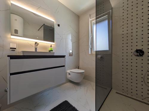 une salle de bain avec toilettes, lavabo et miroir dans l'établissement Seaside Serenity "Rose" with pool, 150m from sea, à Sukošan