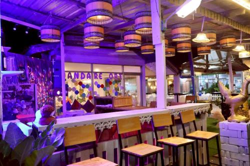 a bar with wooden stools in a restaurant with purple lighting at The Nanda Beach Resort in Sikao