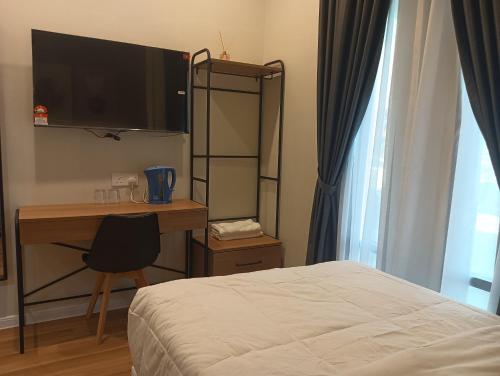 a bedroom with a bed and a desk with a television at Karasky Hotel in Simpang Ampat