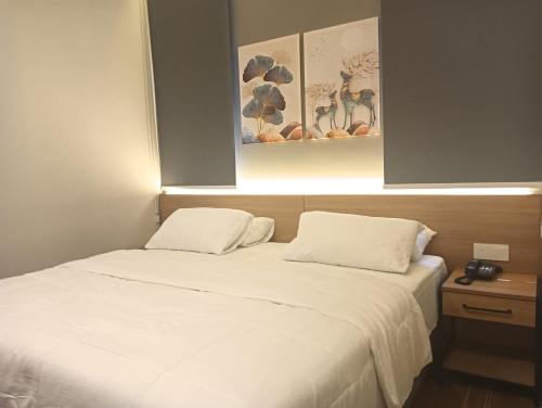 a bed with white sheets and pillows in a room at Karasky Hotel in Simpang Ampat