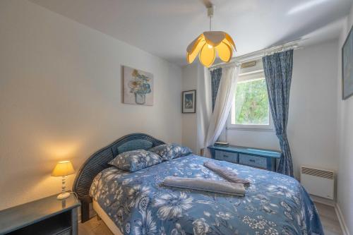 une chambre avec un lit avec une couverture bleue et une fenêtre dans l'établissement Apartment with parking and balcony near the beach, à Deauville