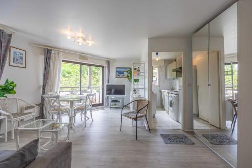 un salon avec une table et des chaises et une cuisine dans l'établissement Apartment with parking and balcony near the beach, à Deauville