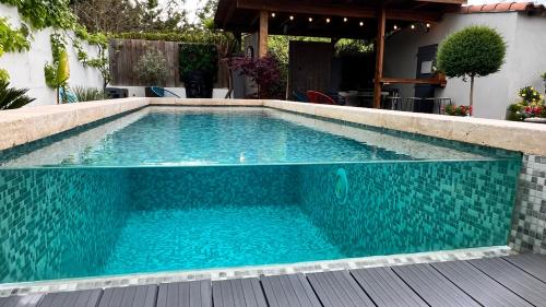 une piscine avec de l'eau bleue dans une cour arrière dans l'établissement Très belle maison avec piscine , proche centre ville - Aix en Provence, à Aix-en-Provence