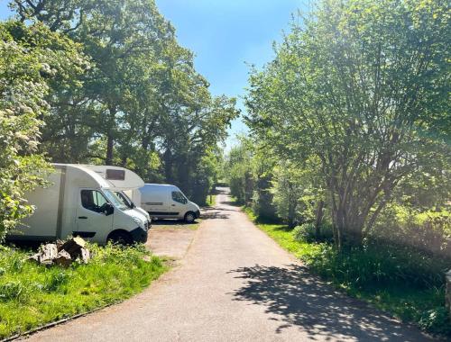 two vehicles parked on a dirt road next to trees at Peaceful Three Bed Country Apartment in Nuthurst