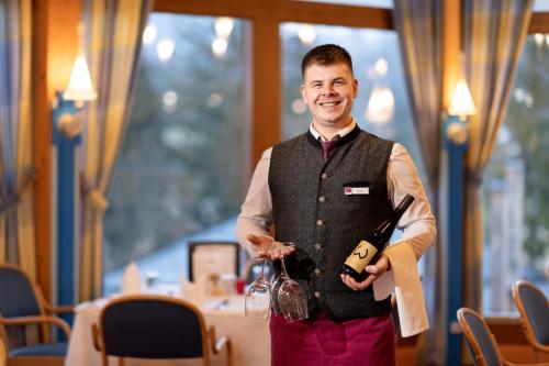 a man holding a bottle of wine in a restaurant at Vivea Gesundheitshotel Bad Häring in Bad Häring