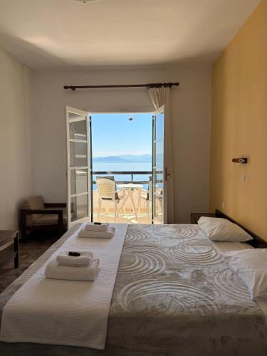 a bedroom with a bed with a view of the ocean at Nikoli Apartments in Benitses