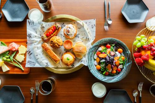 a wooden table with plates of food and bowls of fruit at HOTEL RIN TOKYO - Private Townhouse - in Tokyo