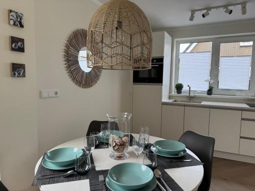 a dining room with a table and a chandelier at HÜBSCHES FERIENHAUS IN OUDDORP - fußläufig zum Strand und Zentrum in Ouddorp