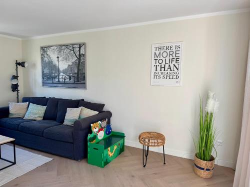 a living room with a blue couch and a table at HÜBSCHES FERIENHAUS IN OUDDORP - fußläufig zum Strand und Zentrum in Ouddorp