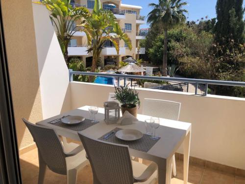 a white table and chairs on a balcony at Stylish 1BR Apt With Pool - Near Mall, Restaurants & Shops in Paphos