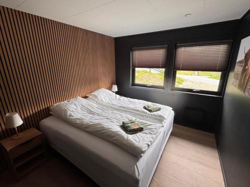 a bedroom with a bed and two windows at House near Odda, Dronningstien and Trolltunga in Hovland