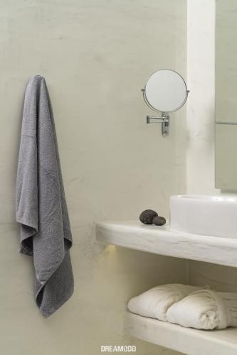 a bathroom with a sink and a towel hanging on a wall at Edem Boutique Suites in Oia