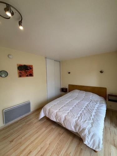 a bedroom with a white bed and a wooden floor at StudiosMichel apt 17 balcon thermes 400m à pied in Cazaubon