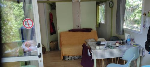 Cette petite chambre comprend une table et un lit. dans l'établissement Chalet dans Camping 3 étoiles à Vogüé, à Vogüé