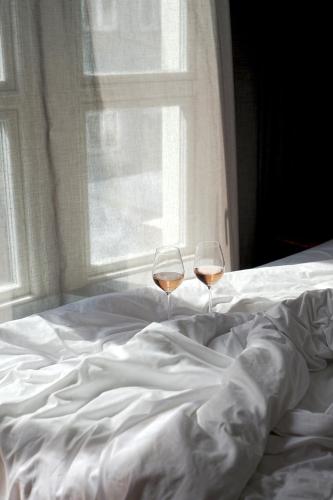 two glasses of wine sitting on top of a bed at Hotel SP34 in Copenhagen