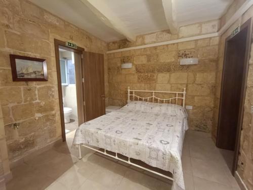 Un dormitorio con una cama en una pared de piedra. en Kalkara Maisonette in the Alley, en Kalkara