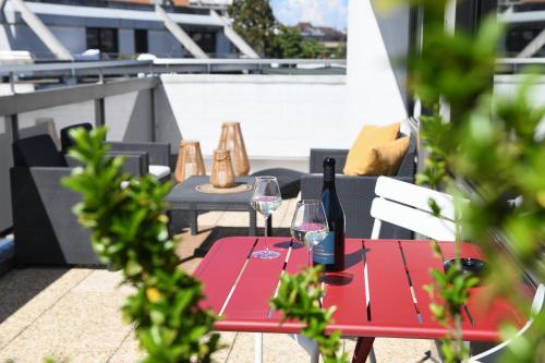 a red table with wine glasses on a balcony at Home Swiss Hotel in Geneva