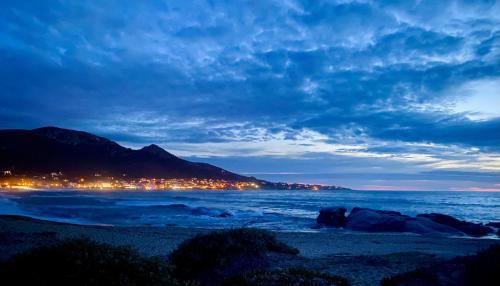 a view of a beach at night with a city at Hotel L'ondine in Algajola