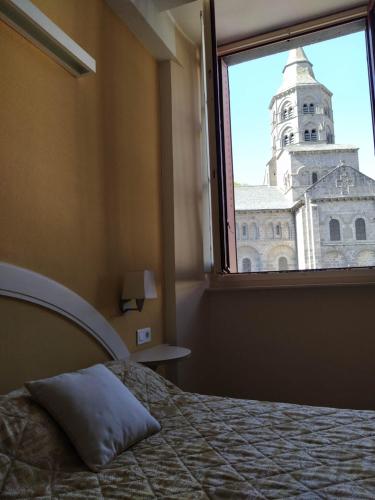 a bedroom with a bed and a window with a clock tower at Hôtel restaurant Notre Dame in Orcival