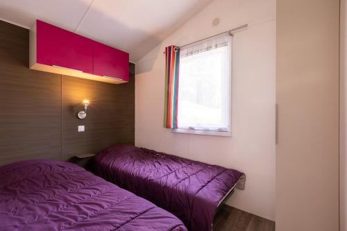 une chambre avec un lit violet et une fenêtre dans l'établissement Camping les Alouettes - Bretignolles-sur-Mer, à Bretignolles-sur-Mer